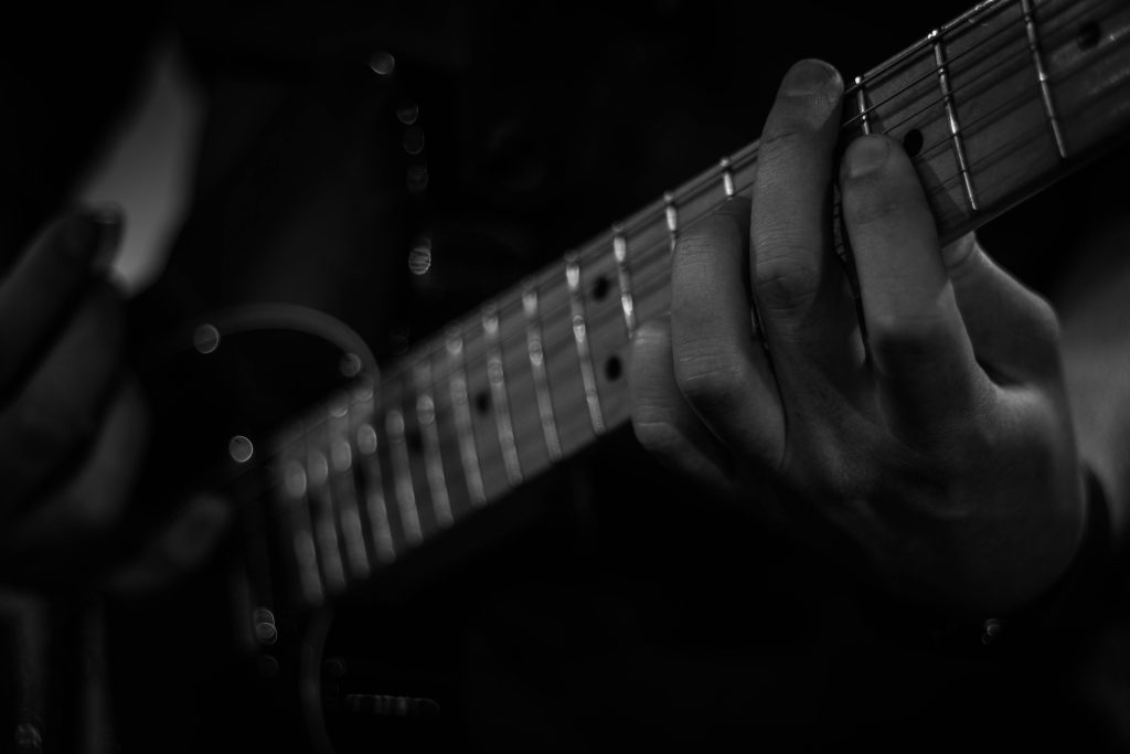 Fingers on an electric guitar fretboard.